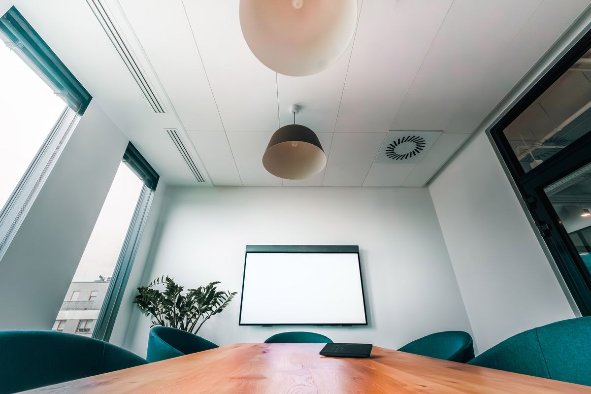 Bright, empty conference room with a wooden table and teal chairs, ready for the next workday