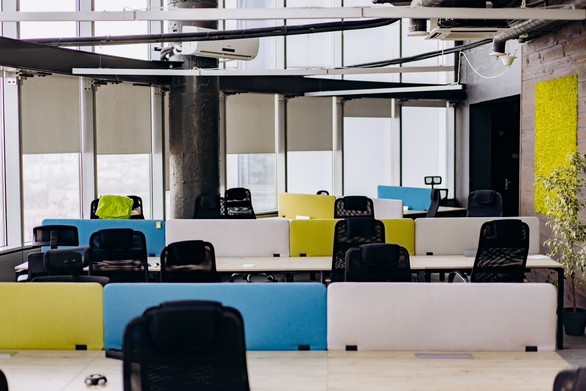 Bright coworking space with shared hot desks, colorful dividers and large windows
