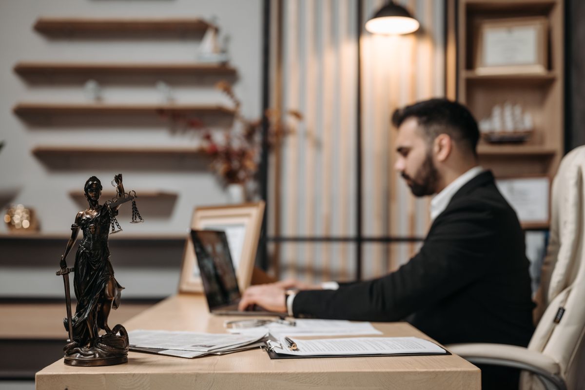Attorney working at a tidy desk in a modern law office with a Lady Justice statue