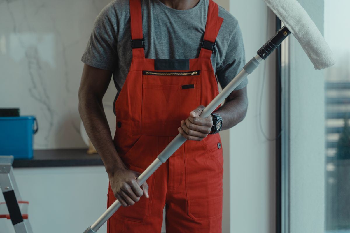 Professional cleaner in uniform holding a mop in a commercial space