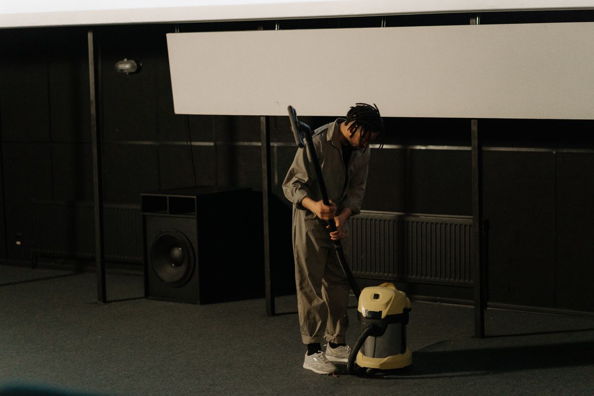 Worker in coveralls vacuuming the floor of an empty hall