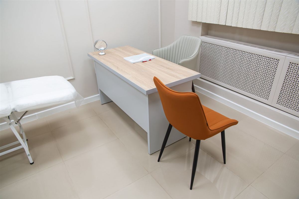 Clean treatment room with a padded table, desk and tile floor